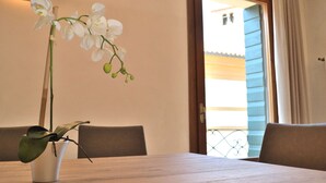A dining table with a potted orchid, a wooden chair, and a view of a balcony. - DARK PORCH DELUXE APARTMENT - HISTORIC CENTER (Treviso)
