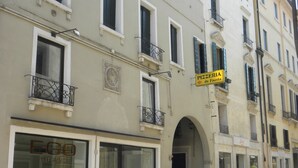 A multi-story building with a ground-floor shop named "PIZZERIA da Fausta" and a visible storefront with large glass windows. - DARK PORCH DELUXE APARTMENT - HISTORIC CENTER (Treviso)