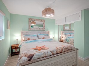 Une chambre à coucher avec un lit en bois, un grand miroir et un luminaire fixé au plafond.