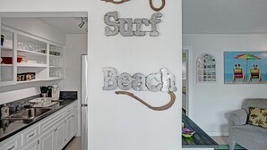 A kitchen with white cabinets, a stainless steel refrigerator, and a wooden dining table.