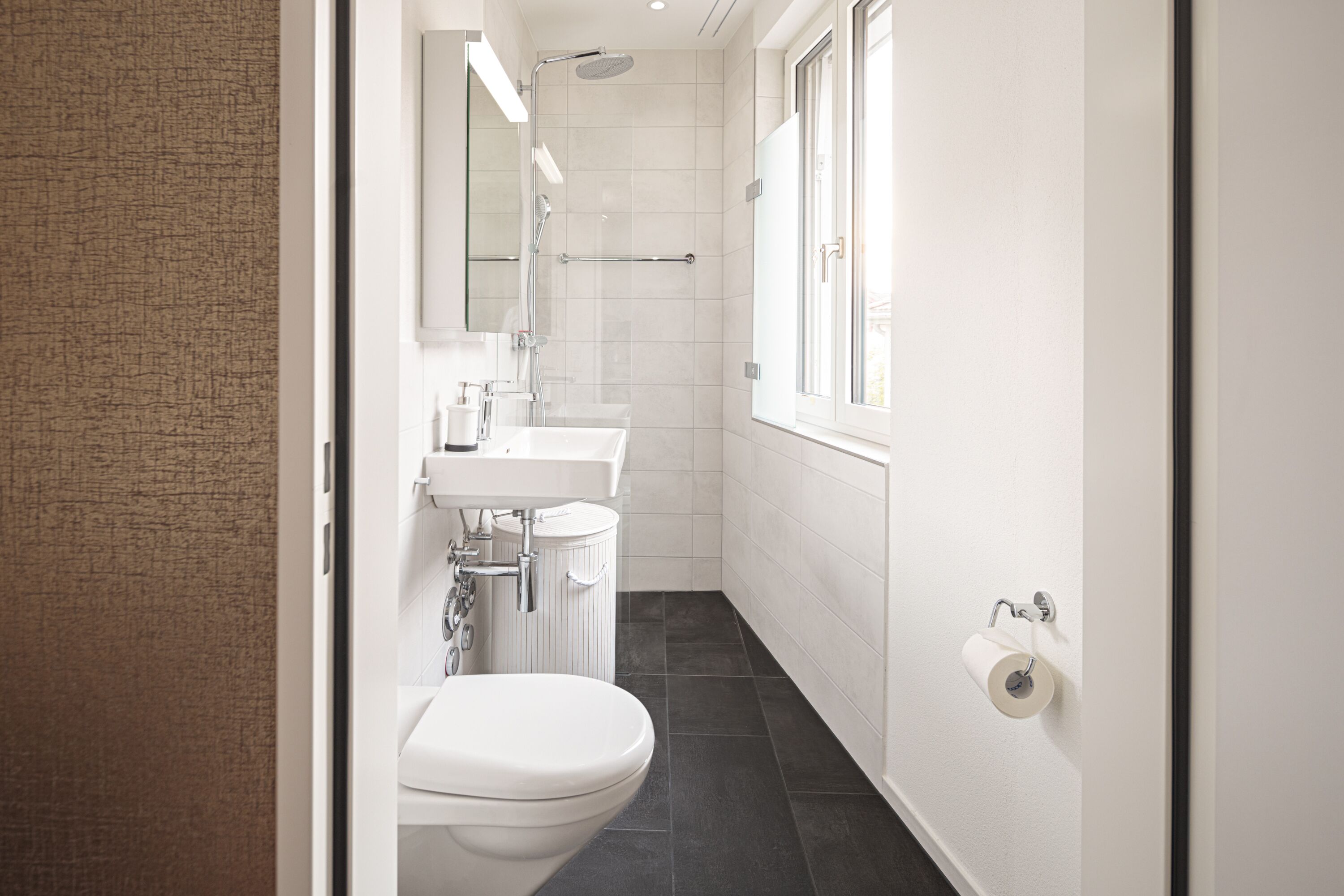 A modern bathroom with a toilet, sink, and shower.