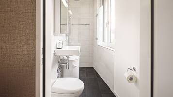 A modern bathroom with a toilet, sink, and shower.