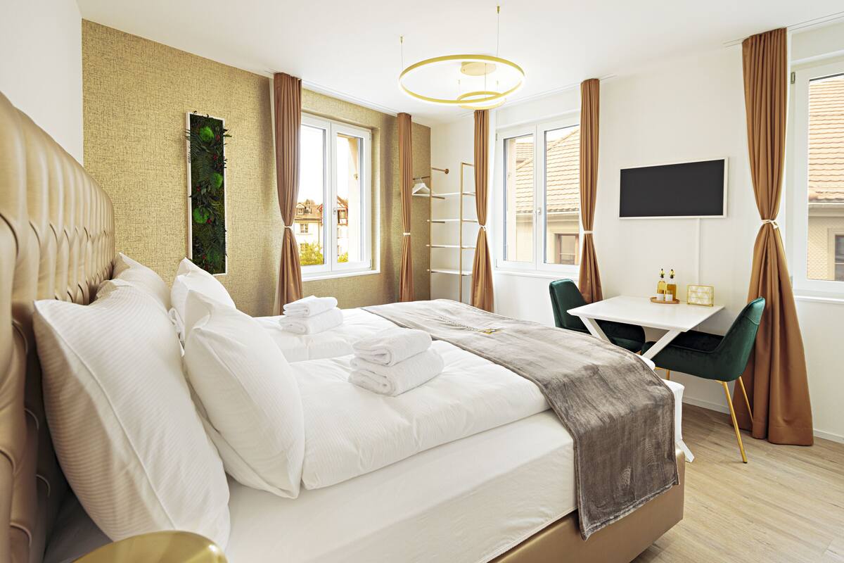 A hotel room with a bed, a desk, and a TV.