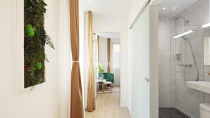 Un baño moderno con cabina de ducha de vidrio, un lavabo blanco y piso cubierto de baldosas oscuras.