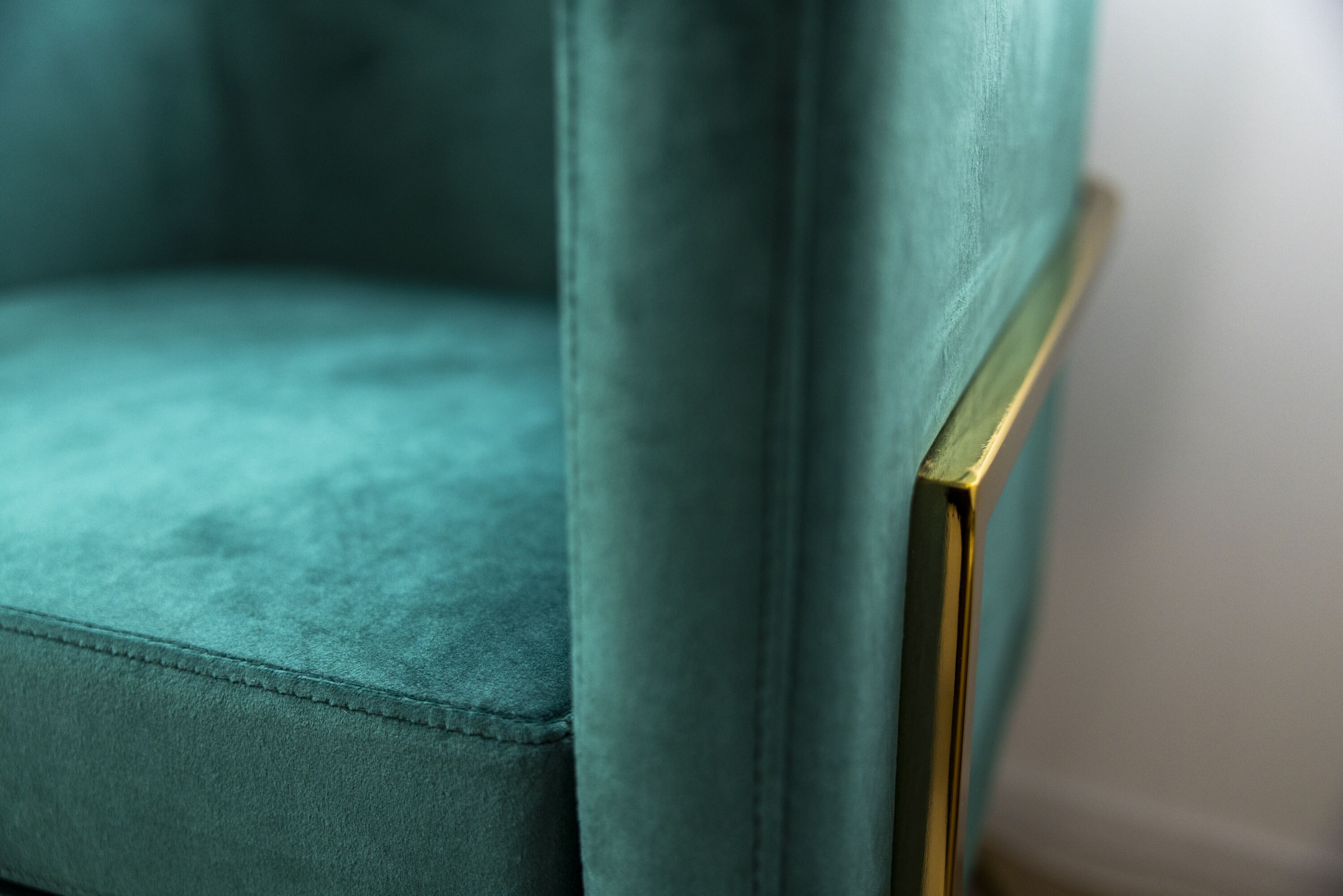 A close-up of a teal upholstered chair with a gold frame.