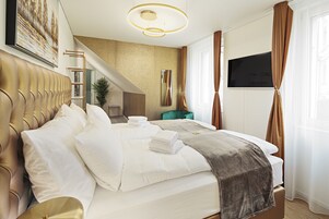 Una habitación de hotel moderna con una cama grande, televisión y una escalera que conduce a un nivel superior.
