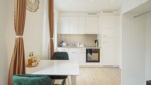 Una cocina moderna con armarios blancos, una mesa de comedor con una silla verde y un reloj en la pared.