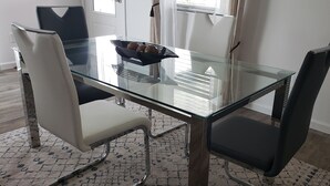 Un comedor moderno con una mesa de vidrio, dos sillas y una bandeja de pasteles.