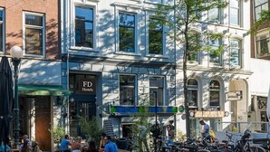 A hotel with outdoor seating, bicycles parked outside, and a sign for 'FD Hotels'.