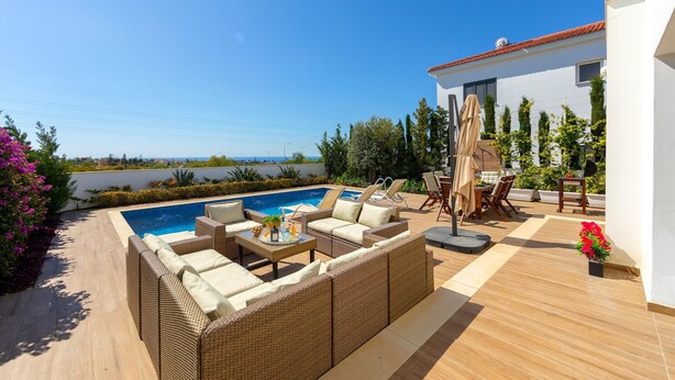 Eine Dachterrasse mit Swimmingpool, Gartenmöbeln und Meerblick.