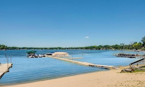 A beach with clear water, a dock, and boats.