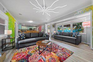 A modern living room with two grey sofas, a colorful rug, and a unique ceiling light. - Spacious 4-Bedroom House with Private Heated Pool (Sarasota County)