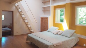 A bedroom with a bed, a window, a door, and a staircase.