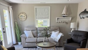 A living room with a sofa, armchair, round coffee table, and a lamp.