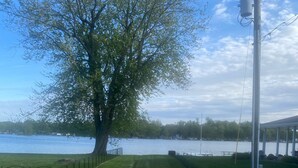 A gravel path leading to a grassy area with a tree and a body of water in the background.