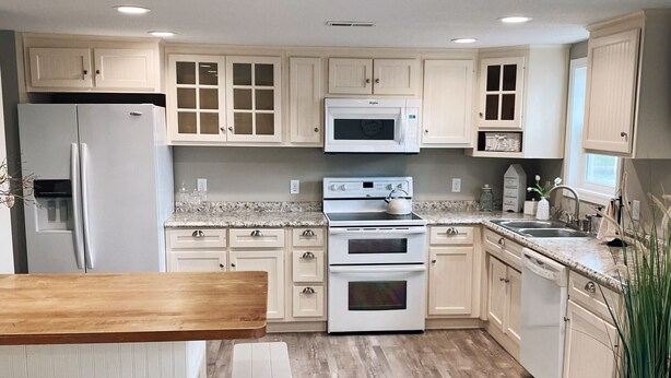 A modern kitchen with white cabinetry, a wooden dining table, and a built-in oven.
