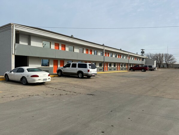 A motel with a row of rooms, a parking lot, and a few cars parked in front.