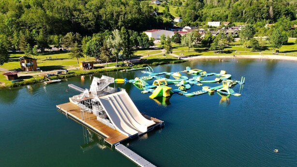 Vista aérea de un parque acuático con un tobogán de agua grande, una terraza de madera y diversos embarcaciones.