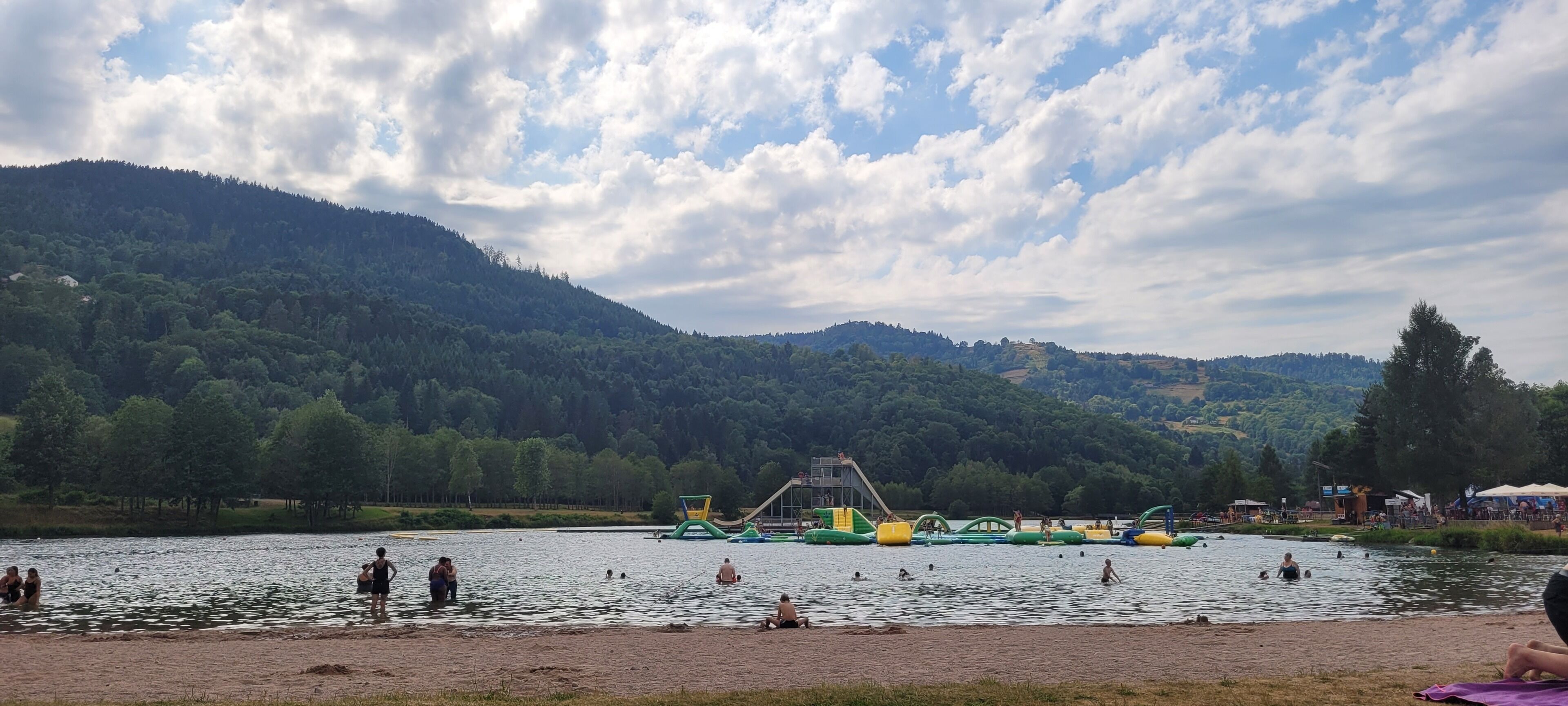A lakeside park with a playground and people swimming.