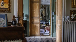 A room with a grand piano, a framed painting, and a chandelier. - Manoir De La Croix Saint Louis (Les Hauts de Forterre)