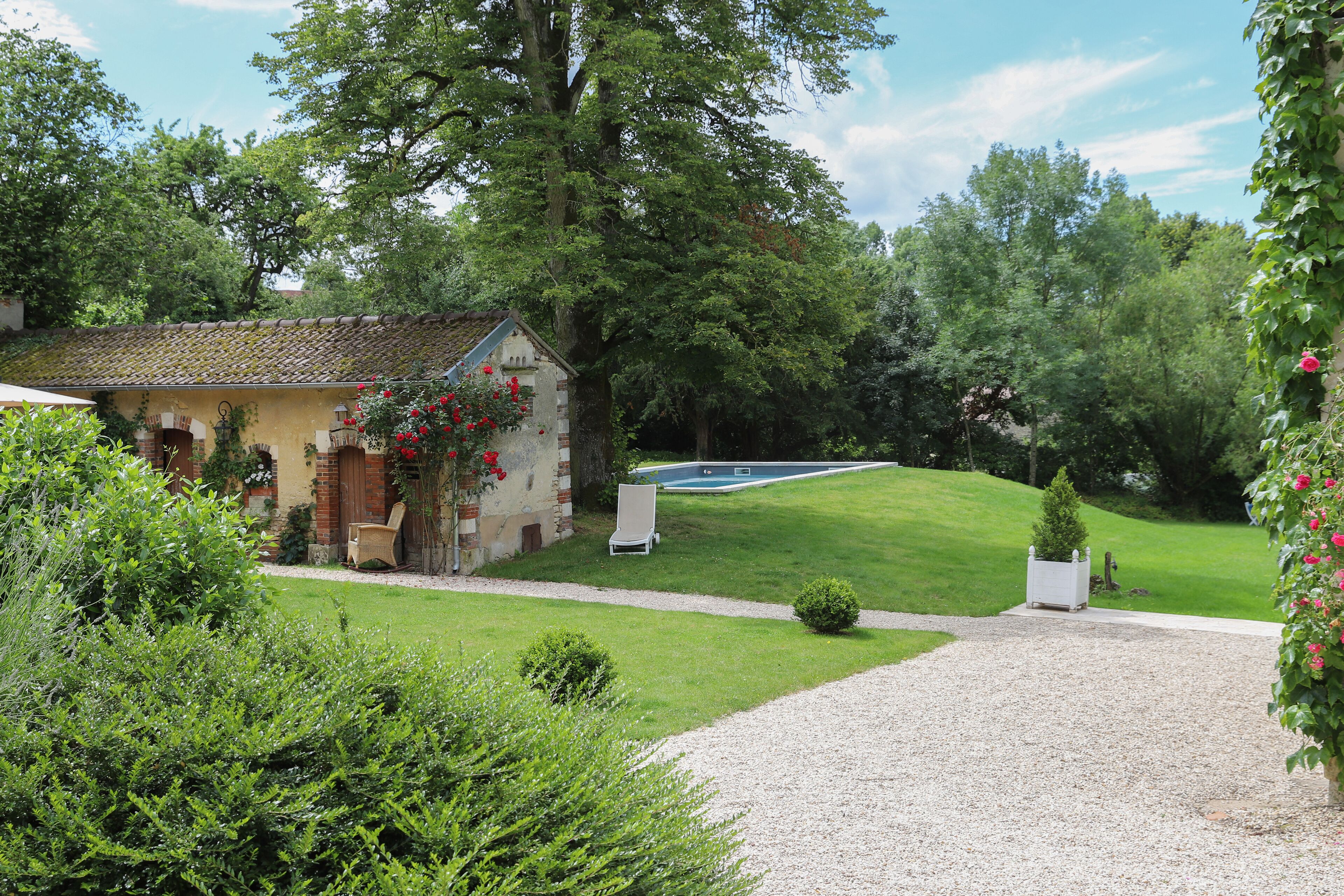 Una casa con jardín, piscina y camino de grava.