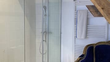 Une salle de bain moderne avec une douche à parois de verre, des murs recouverts de carreaux blancs et une poutre en bois au plafond.