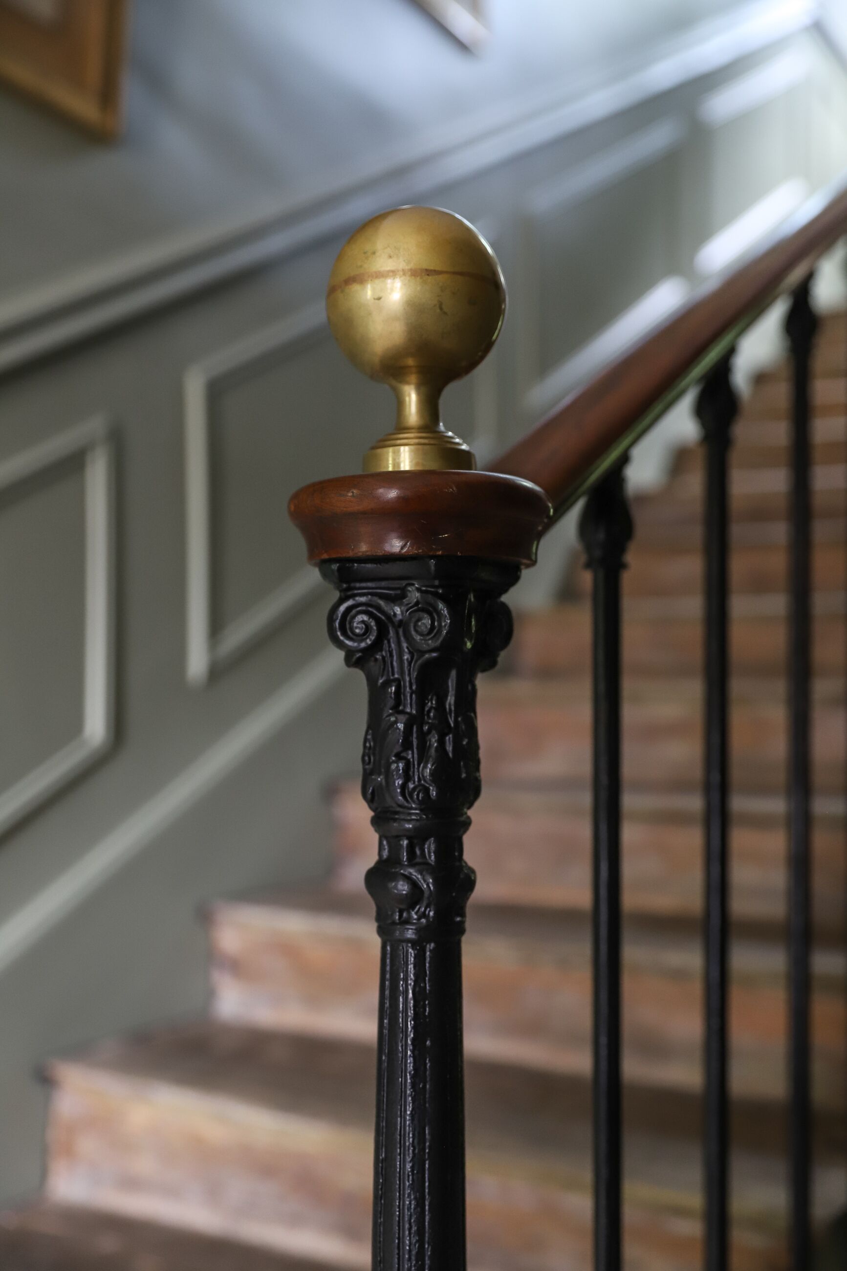 Un escalier orné de balustres noirs et d’un pompon en laiton.