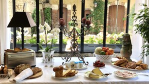 A breakfast table with various foods, a bread toaster, salt and pepper shakers, and a decorative candelabra. - Manoir De La Croix Saint Louis (Les Hauts de Forterre)