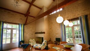 Un salon chaleureux avec une cheminée, des meubles en osier et une table à manger.