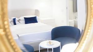 A modern hotel room with a bed, a sofa, a small table, and a mirror. - Tenuta Tropeano (Ricadi)