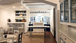 A modern kitchen with a central island, white cabinetry, and a tiled backsplash. - Tenuta Tropeano (Ricadi)