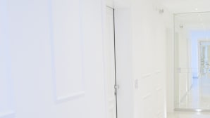 A modern, well-lit hallway with white walls and a glossy floor, leading to a glass door. - Tenuta Tropeano (Ricadi)