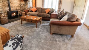 Una sala de estar acogedora con chimenea de piedra, sofás de cuero y una mesa de centro de madera.