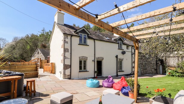 Un patio con pérgola, mobiliario exterior y una botella de champán.