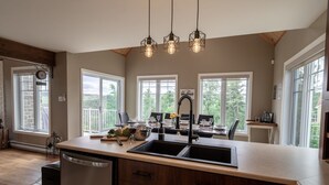 A kitchen with a large island, a dishwasher, and a dining area with a view of the outdoors.