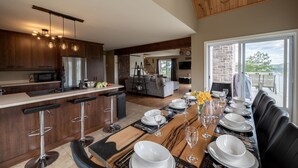 A modern kitchen with dark wood cabinets, a stainless steel refrigerator, and a bar area with stools.