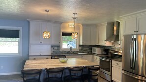 A kitchen with a large island, stainless steel appliances, and pendant lighting. - WATERFRONT Vacation! {3 bed 2 bath.  Sleeps 13} (Goreville)