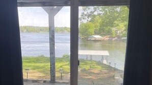 A room with a large sliding glass door leading to a view of a lake and a dock. - WATERFRONT Vacation! {3 bed 2 bath.  Sleeps 13} (Goreville)