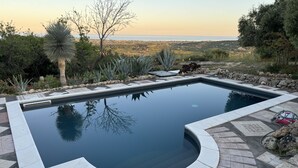 A rectangular swimming pool with a curved edge, surrounded by a stone patio. - Villa Cava with private pool (Avola)