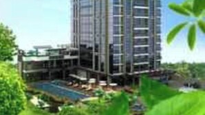 Un immeuble de grande hauteur doté de nombreux balcons, entouré de verdure et surplombant un ciel dégagé.