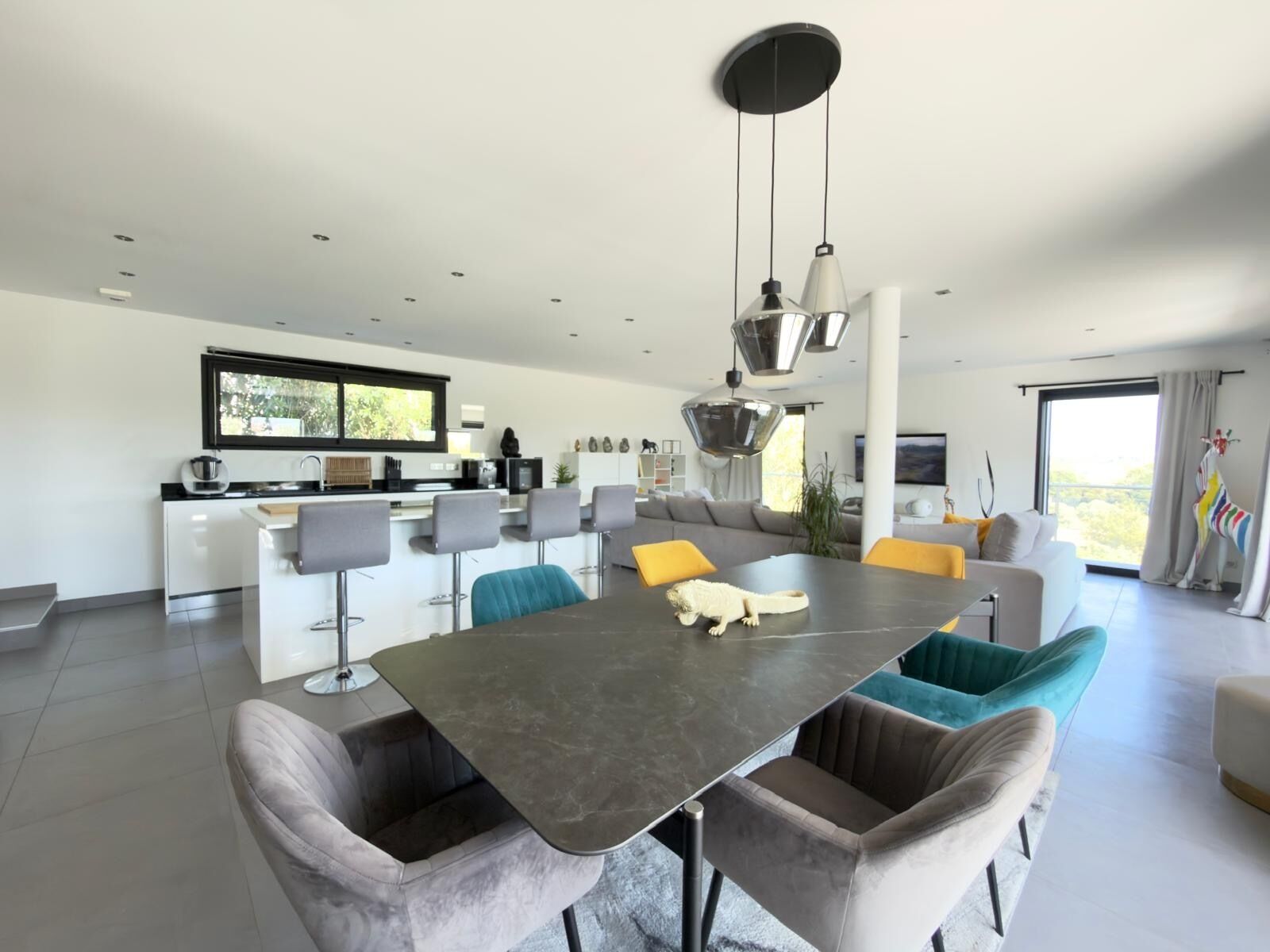 A modern kitchen with a dining area, a large window, and a view of the outdoors.