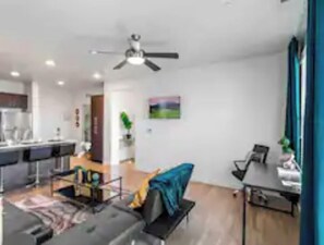 Enjoy a comfortable stay in this stylish living space with a dining area, sofa, and ceiling fan.