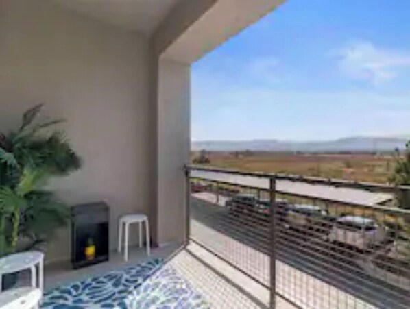 Enjoy the scenic view of the railway track and surrounding landscape from this balcony's seating area.