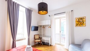 A bedroom with a red bed, a wooden chair, a white wardrobe, a desk, and a hanging light fixture. - Barrio 133 - Double bedroom in center (Napoli)