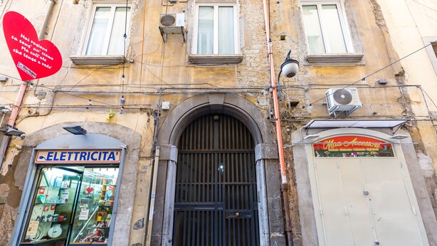 A building facade with an 'ELETTRICITA' shop, a barred entrance, and a red heart-shaped sign with text. - Barrio 133 - Double bedroom in center (Napoli)