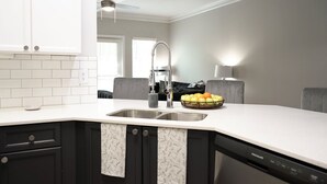 Una cocina moderna con encimera blanca, armarios negros y lavavajillas integrado.