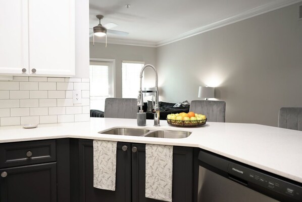A modern kitchen with a white countertop, black cabinets, and a built-in dishwasher.