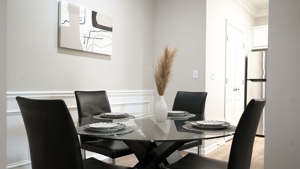 A dining area with a glass table, black chairs, and a vase with dried plants. - Luxury Modern Apartment In Atlanta wFree Parking  (Atlanta)
