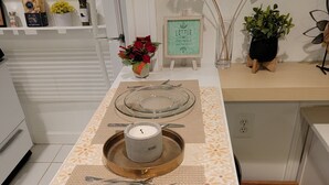 A kitchen with a long table set for two, featuring clear glass plates, silverware, and a candle labeled "HERBS". - Great Delray, Alexandria, One bed, bath, kitchen NOT share, big backyard, metro, (Alexandria)