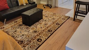 A modern living room with a black leather sofa, a patterned rug, and a small black ottoman. - Great Delray, Alexandria, One bed, bath, kitchen NOT share, big backyard, metro, (Alexandria)